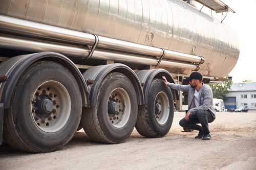 Truck driver inspecting wheels